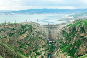montanha panorama com ampla arqueado hidroelétrica barragem e uma reservatório dentro a desfiladeiro foto