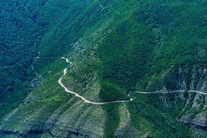 enrolamento sujeira estrada ao longo uma arborizado montanha declive dentro uma terras altas área foto