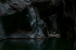 limpar \ limpo subterrâneo caverna rio dentro íngreme pedra bancos dentro a Sombrio foto