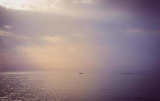 três canoas navegando no mar durante o pôr do sol foto
