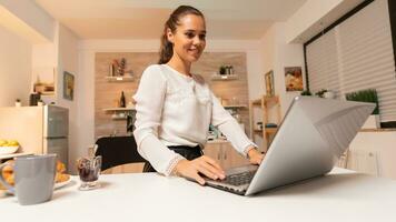 ocupado empresária comunicando com potencial cliente às noite usando computador portátil. concentrado empreendedor dentro casa cozinha usando caderno durante atrasado horas dentro a tarde. foto