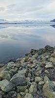 gelado aberto água e Nevado declives dentro islandês contexto, escandinavo congeladas lago dentro nórdico Islândia panorama. majestoso cenário com Rocha formações e gelo fragmentos. foto