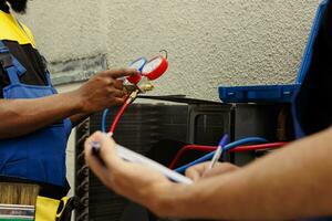 temperado wiremen Perguntou para Faz hvac sistema verificar, reenchimento refrigerante. qualificado eletricistas colegas usando múltiplo Manômetros para exatamente calibrar a pressão dentro externo ar condicionador foto