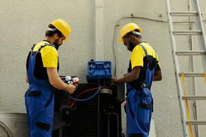 profissional trabalhadores fixação quebrado ventilador ventilador causando congeladas evaporador bobina, resultante dentro reduzido resfriamento desempenho. qualificado eletricistas otimizando condensador capacidade foto