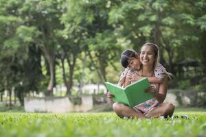 mãe e filha lendo um conto de fadas para a filha no parque foto