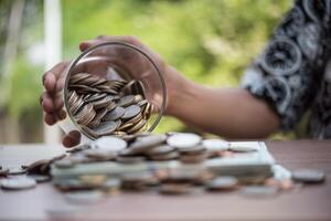 mão colocando moedas na jarra com a etapa da pilha de dinheiro crescendo e economizando dinheiro foto