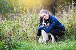 menina sentada abraçando com seu cachorro foto