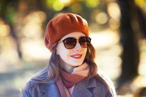 mulher de boina laranja e óculos de sol no parque outono