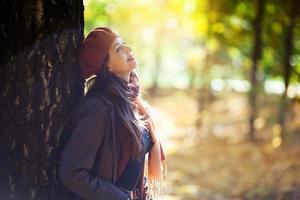 garota de boina ao lado de uma árvore em um dia ensolarado de outono foto