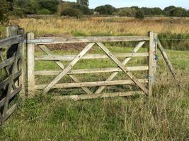 portão de fazenda de madeira em um campo gramado foto