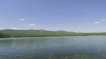 lindo azul Claro água em a costa do a lago. floresta panorama às costa espelhado dentro água foto