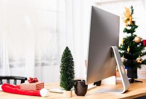 mesa de escritório ou local de trabalho com computador moderno e decoração de caixa de presente de Natal. foto