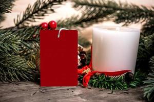 maquete tag cartão de papel com decoração de Natal de vela no fundo da mesa de madeira. foto