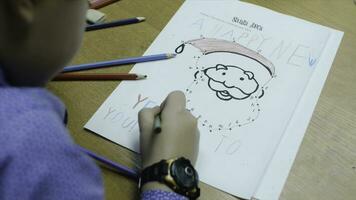 Alto ângulo Visão do Garoto desenhando com cor lápis em papel às escrivaninha dentro sala de aula. grampo. uma fofa pequeno Garoto desenhando com uma lápis fechar acima foto