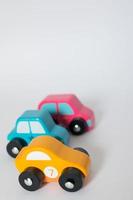 carrinhos de brinquedo de madeira nas cores amarelo, azul e rosa, fundo branco foto