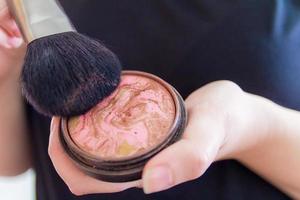 close-up das mãos de uma mulher segurando um bronzeador de maquiagem foto