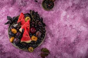 sortimento do roxa fruta ameixa, uva, mirtilo e manjericão foto