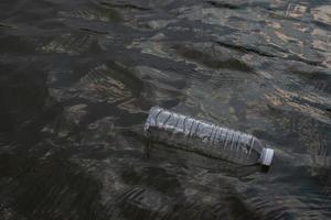 garrafa de plástico residual usada flutuando na água em um canal, conceito ambiental e de poluição de abordagem ecológica foto
