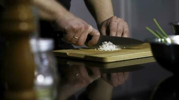 fechar acima do homem mãos corte branco cebola em uma de madeira cortar borda com uma cozinha faca. arte. preparando saudável Comida. foto