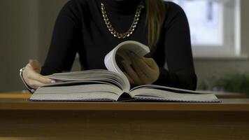 mulheres mãos folheando através uma livro. mulher sentado às a mesa folheando através a livro foto