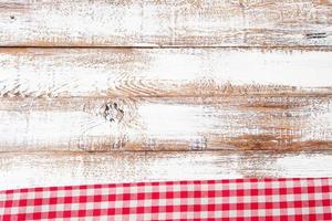toalha de mesa quadriculada vermelha na velha mesa de madeira, conceito de férias foto