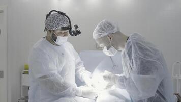cirurgiões trabalhos durante Operação. Ação. dois profissional cirurgiões estão silenciosamente realizando Operação. dois cirurgiões executar Operação dentro calma meio Ambiente foto