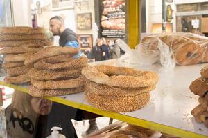 Atenas, Grécia, dezembro 23, 2023 mulher rua fornecedor vendendo a saboroso Koulouri ou pão argolas uma tradicional grego rua Comida encontrado através Atenas foto