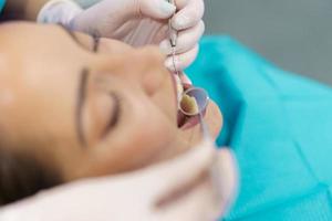 dentista verificando o interior dos dentes de seu paciente com um espelho dental. foto