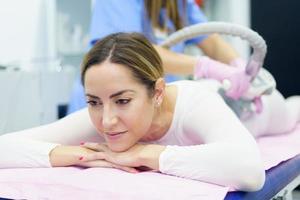mulher em um terno branco especial fazendo massagem anticelulite com aparelho de spa foto