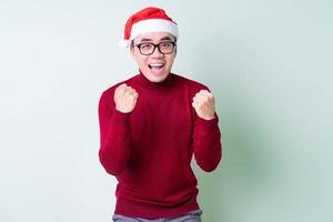 jovem asiático com chapéu de natal em fundo verde foto