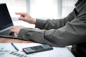 o negócio homem usar computador computador portátil dentro Engenharia Projeto trabalhos com calculadora lápis e desenhando em mesa foto