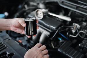 Novo óleo filtro dentro mão uma homem e chave inglesa dentro a Gasolina motor compartimento serviço conceito do carro foto