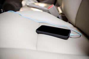 inteligente telefone em a carro assento e cabo conectar para transferir dados para carro rádio e carregar a bateria foto