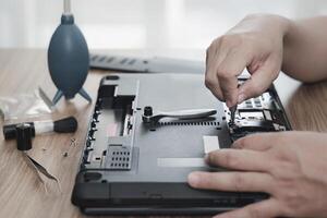 computador alfabetização reparar homens mãos usar Chave de fenda retirar noz do Difícil disco do computador portátil para Verifica e reparar e computador reparar Ferramentas em mesa foto