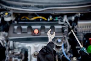 técnico é usando uma chave inglesa e Chave de fenda para reparar carro dentro carro serviço e manutenção conceito foto