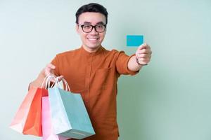 jovem asiático segurando sacola de compras sobre fundo verde foto