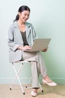 jovem empresária asiática sentada na cadeira sobre fundo verde foto