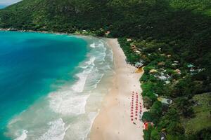 de praia com guarda-chuvas e oceano com ondas dentro santa catarinense. aéreo Visão do feriado de praia foto