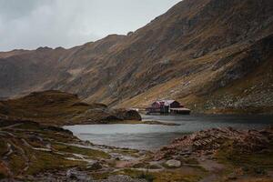 panorama dentro romênia, cárpato montanhas. nebuloso manhã, chuvoso, nublado mau clima. fundo, protetor de tela. lindo natureza, Paz e turismo. lago e casas. foto