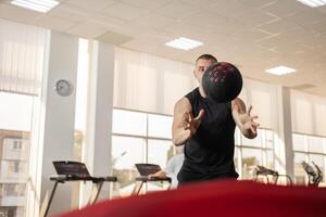 muscular treinador lança a bola em uma trampolim, uma músculo treinador, uma academia. retrato do uma lindo homem, treinamento, Individual peso perda e Esportes cursos. cópia de espaço foto