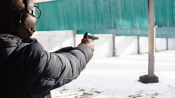 uma homem com fones de ouvido é visando às a alvo. uma homem dentro uma traço incêndios uma pistola. Esportes entretenimento Fora a porta. foto