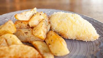 cozido batatas com ervas e costeletas dentro empanamento com queijo e manteiga. Comida em uma prato dentro uma cafeteria. café da manhã, almoço, jantar às a restaurante. lanche foto