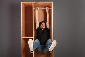 uma homem trava dentro uma armário em uma cano, engraçado, uma teste do a armário de roupa para força. foto
