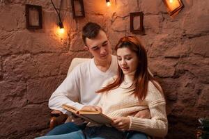 uma casal dentro amor, uma cara e uma menina lendo uma livro. Natal decorações dentro a foto estúdio jovem adolescentes