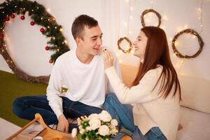 uma jovem feliz casal dentro amor come dentro uma foto estúdio. a cara e a menina estão engraçado alimentando cada outro. posando para modelos dentro uma estúdio para Natal família jantar para Novo anos véspera, café da manhã dentro cama