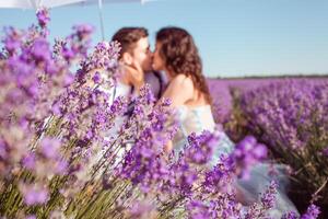 uma casal dentro amor debaixo uma branco guarda-chuva em uma lavanda campo amor foto