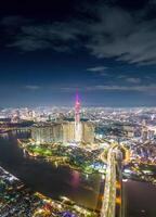 aéreo pôr do sol Visão às ponto de referência 81 - isto é uma super alta arranha-céu e Saigon ponte com desenvolvimento edifícios ao longo Saigon rio, paisagem urbana dentro a noite foto