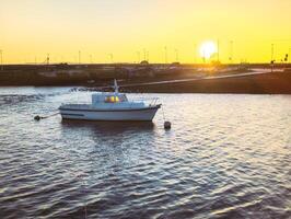 lindo nascer do sol, cenário com velho de madeira barco dentro água às claddagh dentro Galway cidade, Irlanda foto