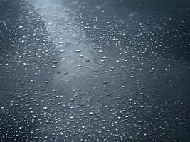 ai gerado pingos de chuva em uma Preto superfície com uma luz brilhando através foto