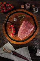 Carne de alcatra crua - picanha brasileira - em uma tábua de madeira com faca e especiarias - vista superior.
